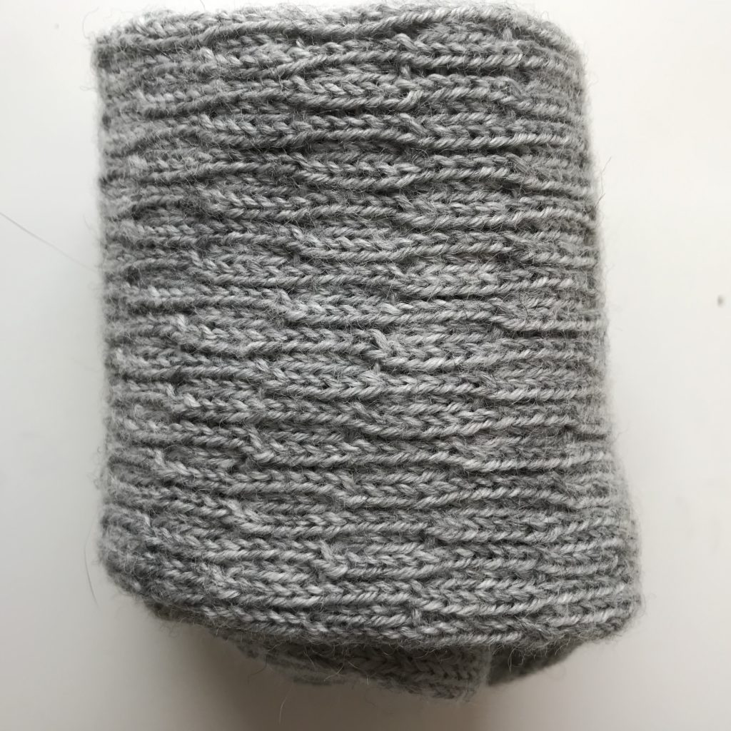 A pair of grey wool knitted socks, rolled into a cylinder shape